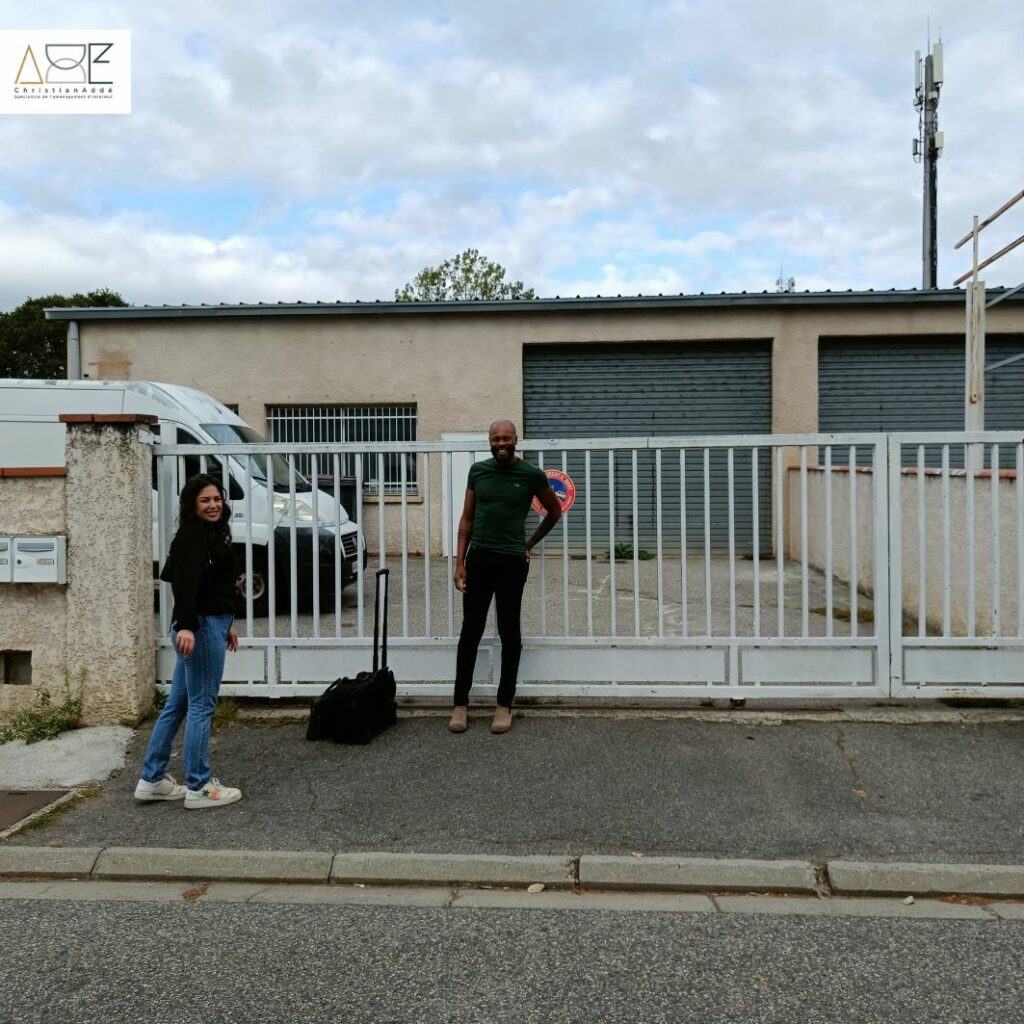 Deux personnes souriantes devant un bâtiment, prêtes à commencer un nouveau projet de rénovation.